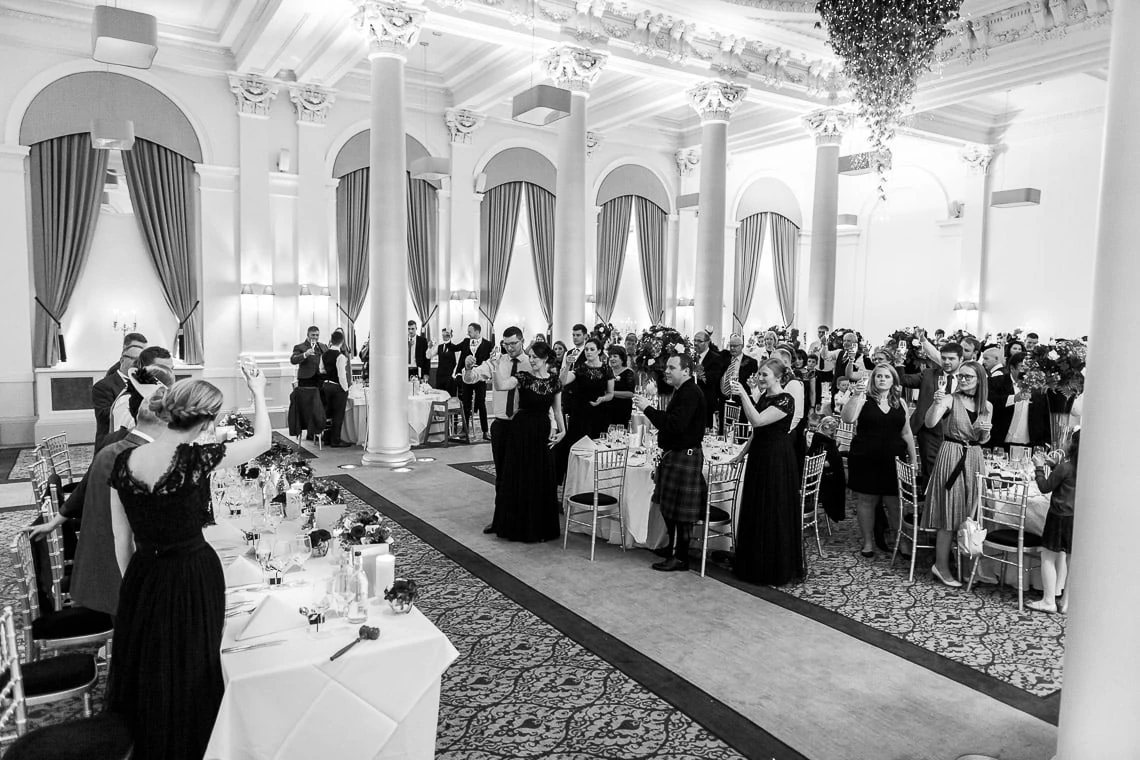 guests raise a toast at the end of father of the bride speech in the King's Hall