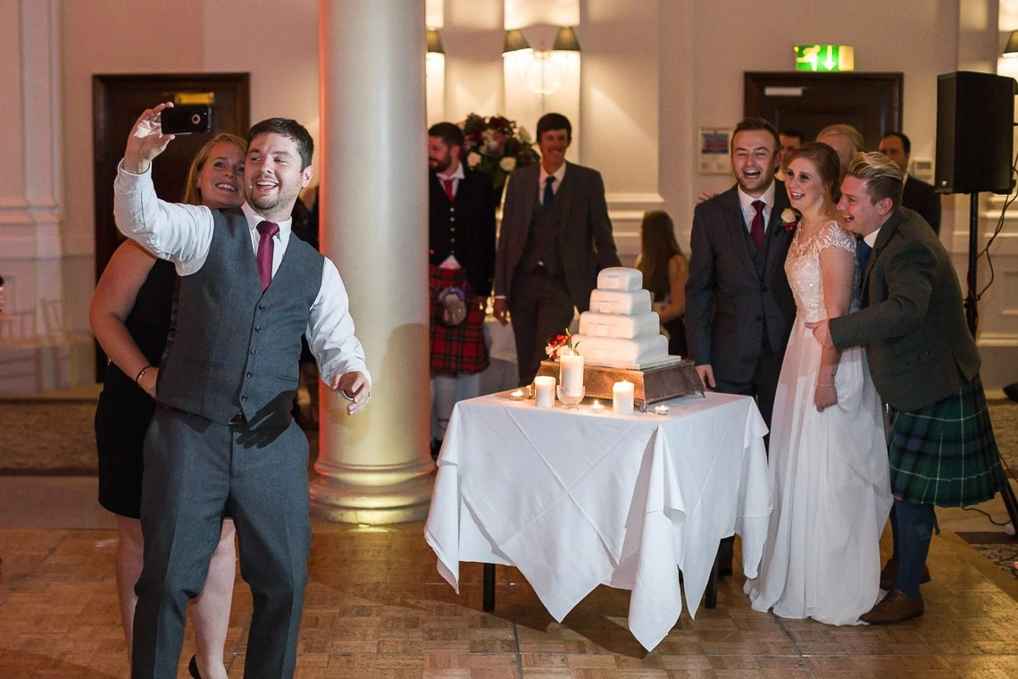 guest selfie as newlyweds cutting the cake in the King's Hall