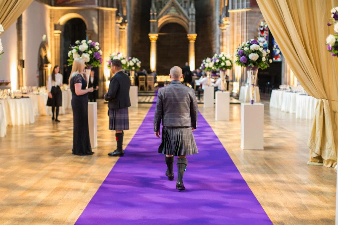 groom walking up the purple carpet aisle