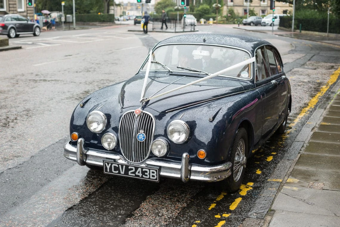 bride arrives in a classic car MK 2 Jaguar