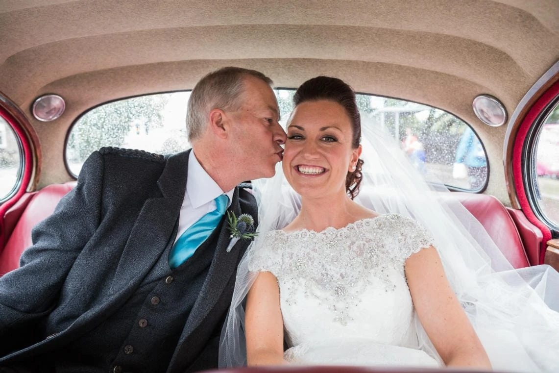 father of the bride kisses his daughter in the back of a classic Mark 2 Jaguar