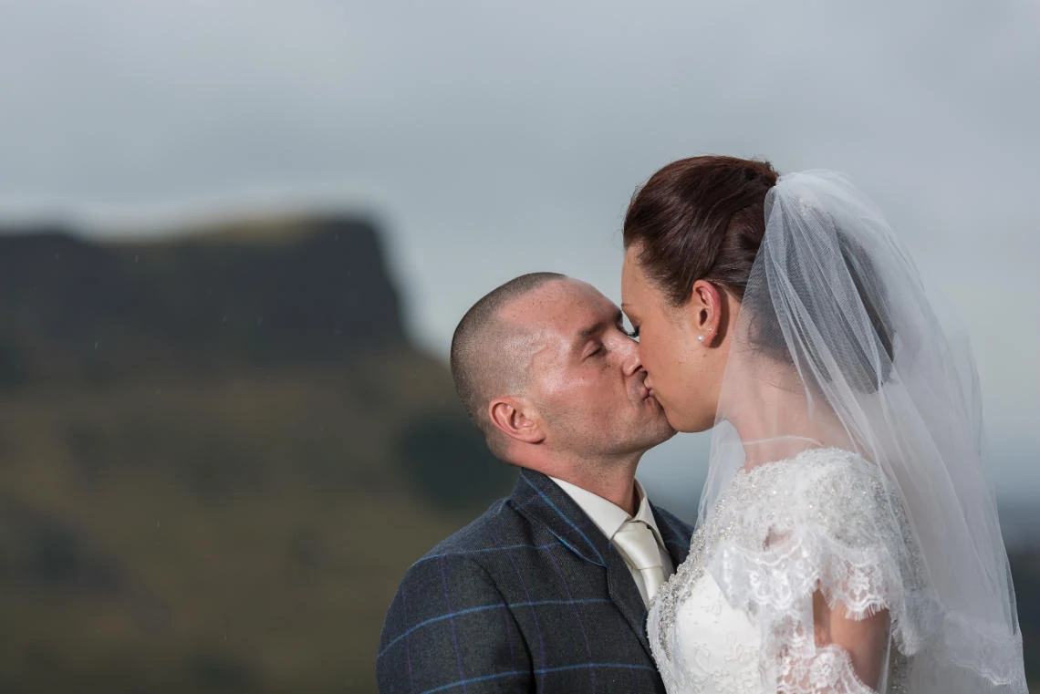 newlyweds kissing on Calton Hill with Arthur's Seat in the background