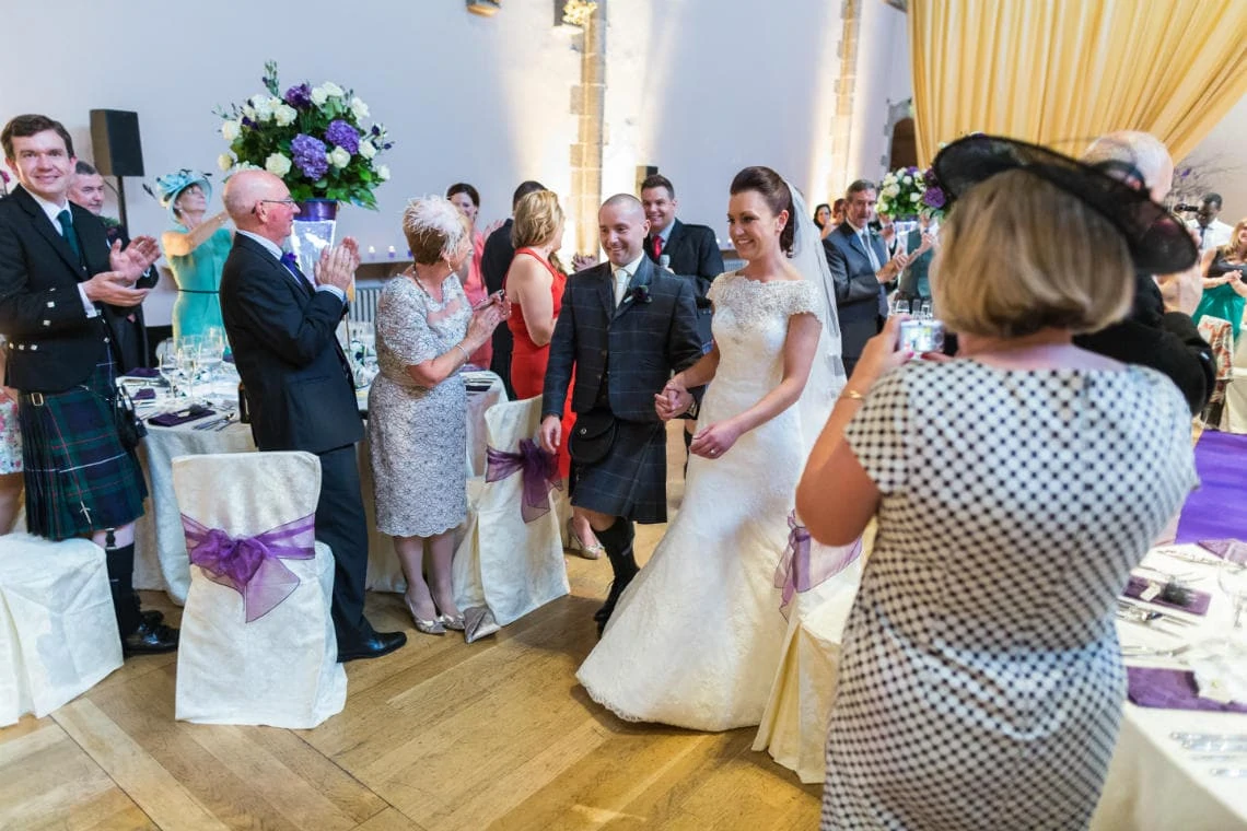 newlyweds make their way to the top table cheered by guests