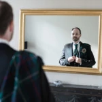 groom looking into a mirror as he adjust his jacket