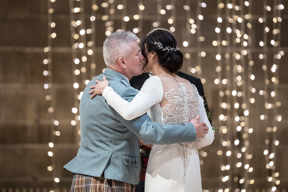 father of the bride kisses his daughter at the altar