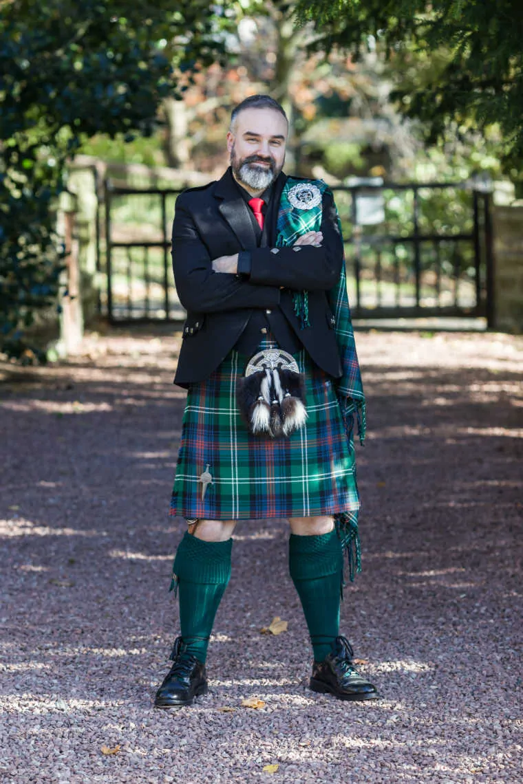 Groom in full highland outfit in the grounds of the Mansion House