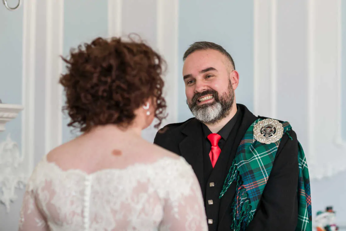 Groom smiling at bride during humanist ceremony in the MacMillan room of the Mansion House