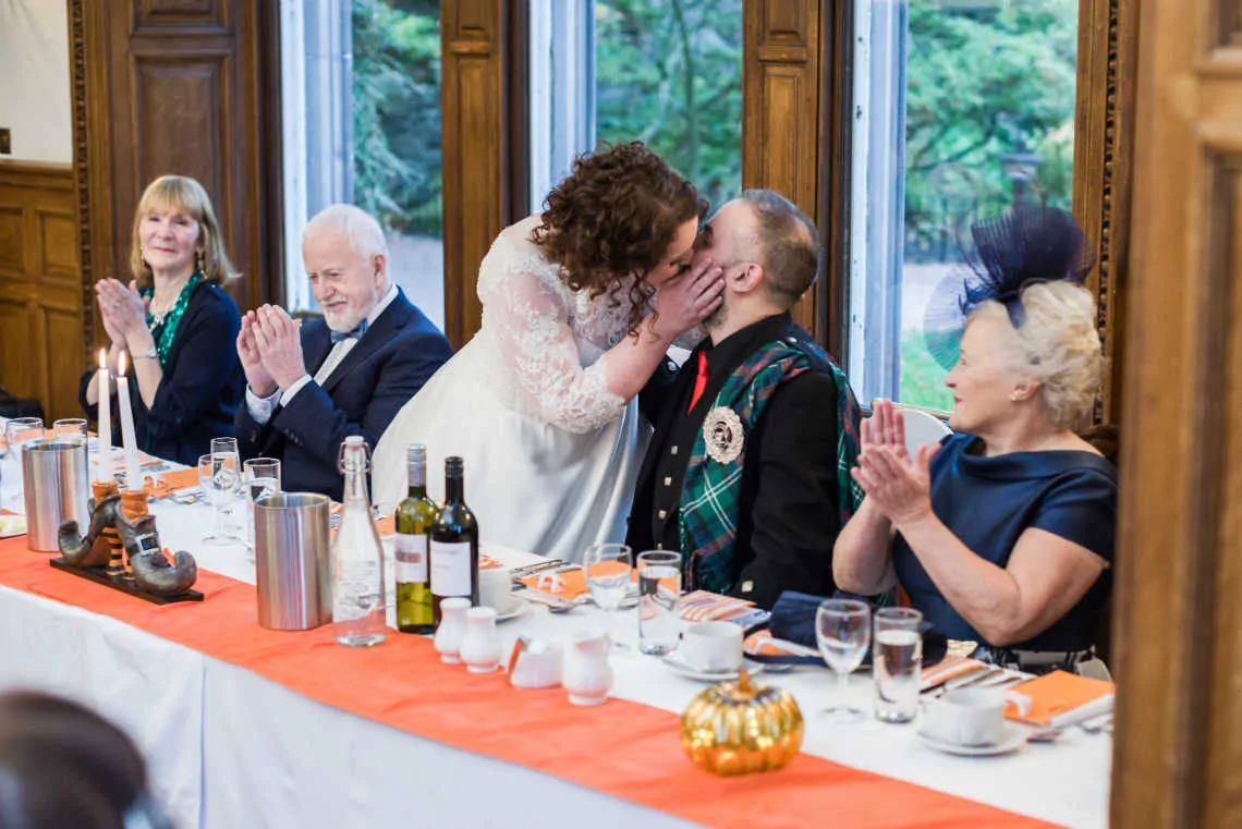 Bride kissing Groom at wedding reception