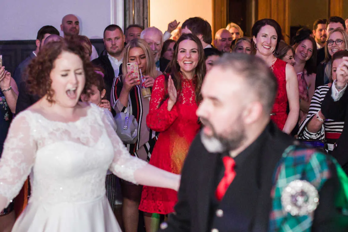 Wedding guests watch bride and groom perform first dance