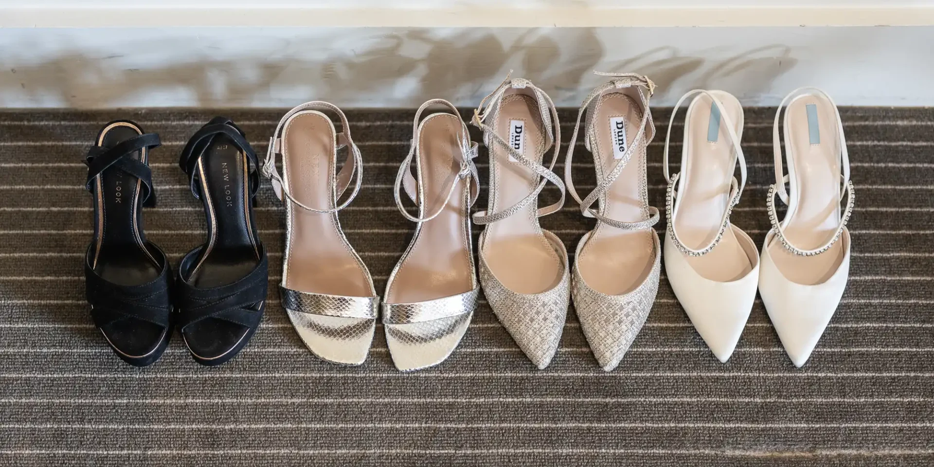 Five pairs of women's high-heeled shoes lined up on a striped carpet.