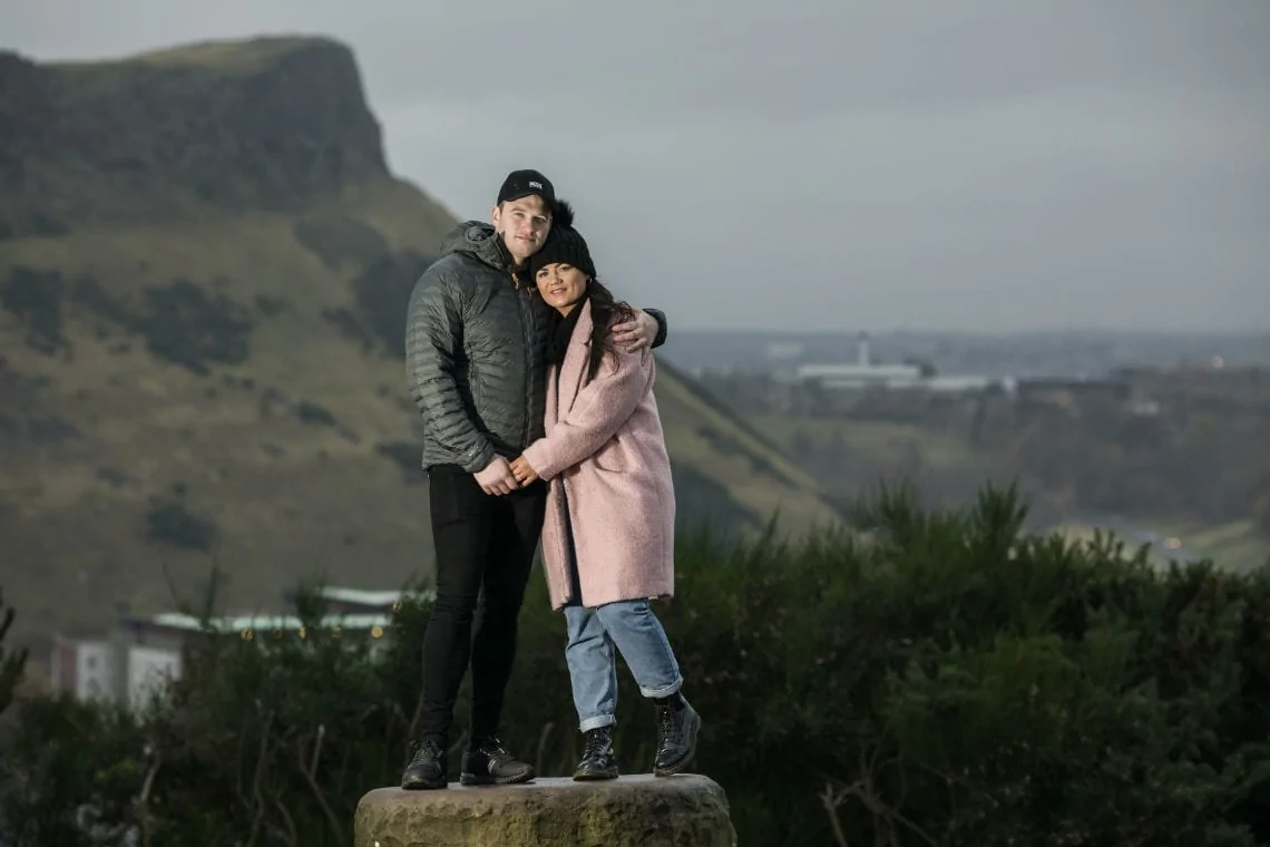 couple embrace with Salisbury Crags in the background