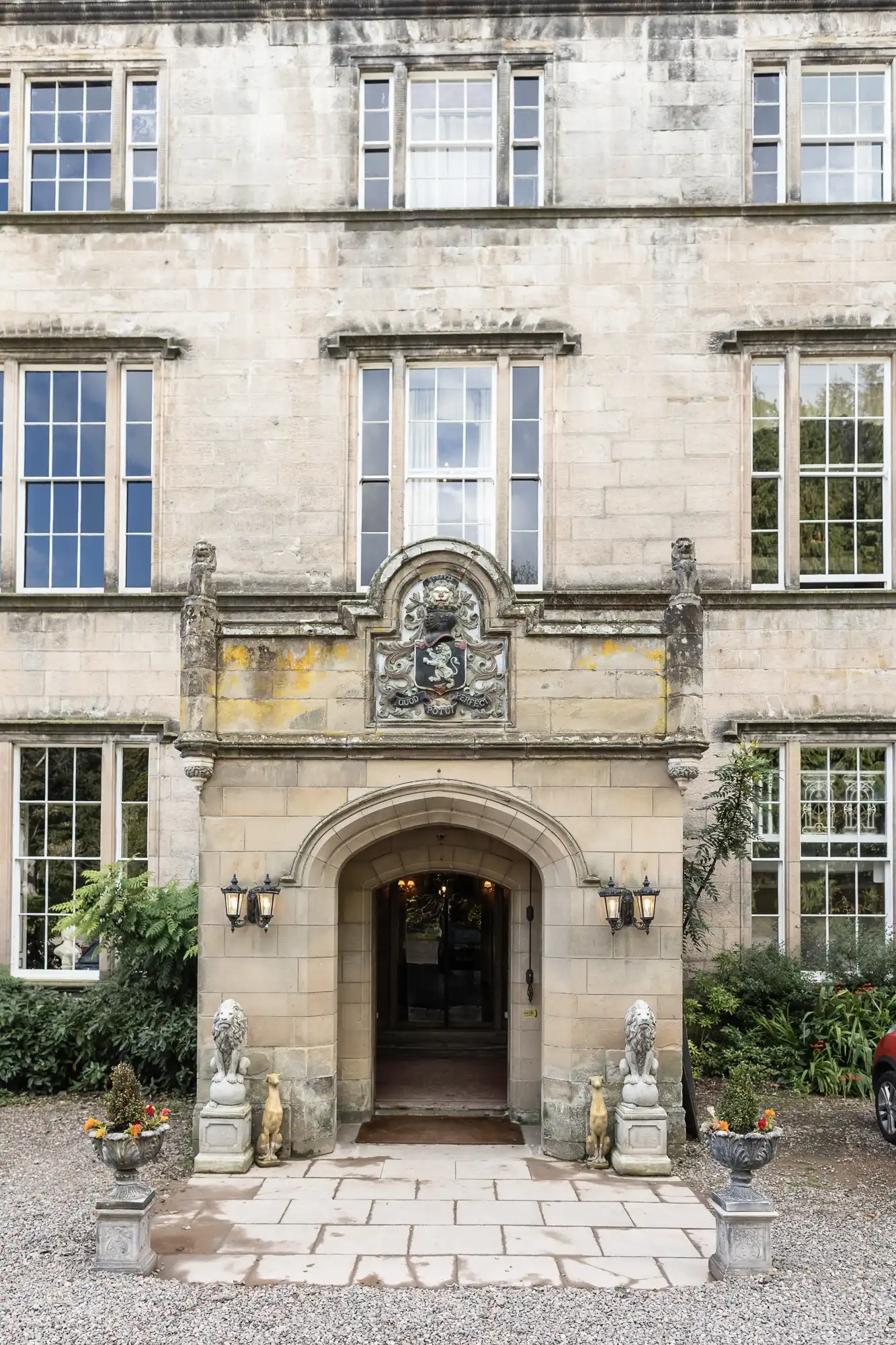 A grand stone building facade with large windows, a decorative entrance featuring ornate sculptures, and two lion statues flanking the doorway.