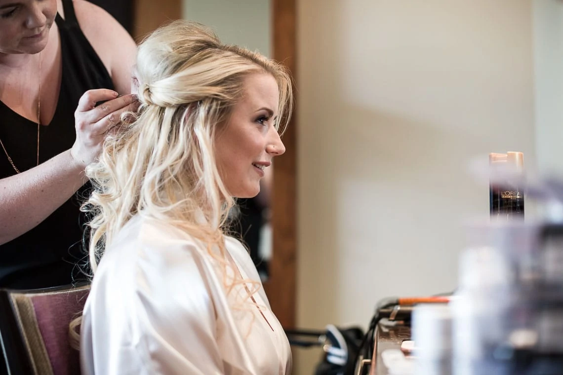 bride looking in mirror whilst getting hair styled
