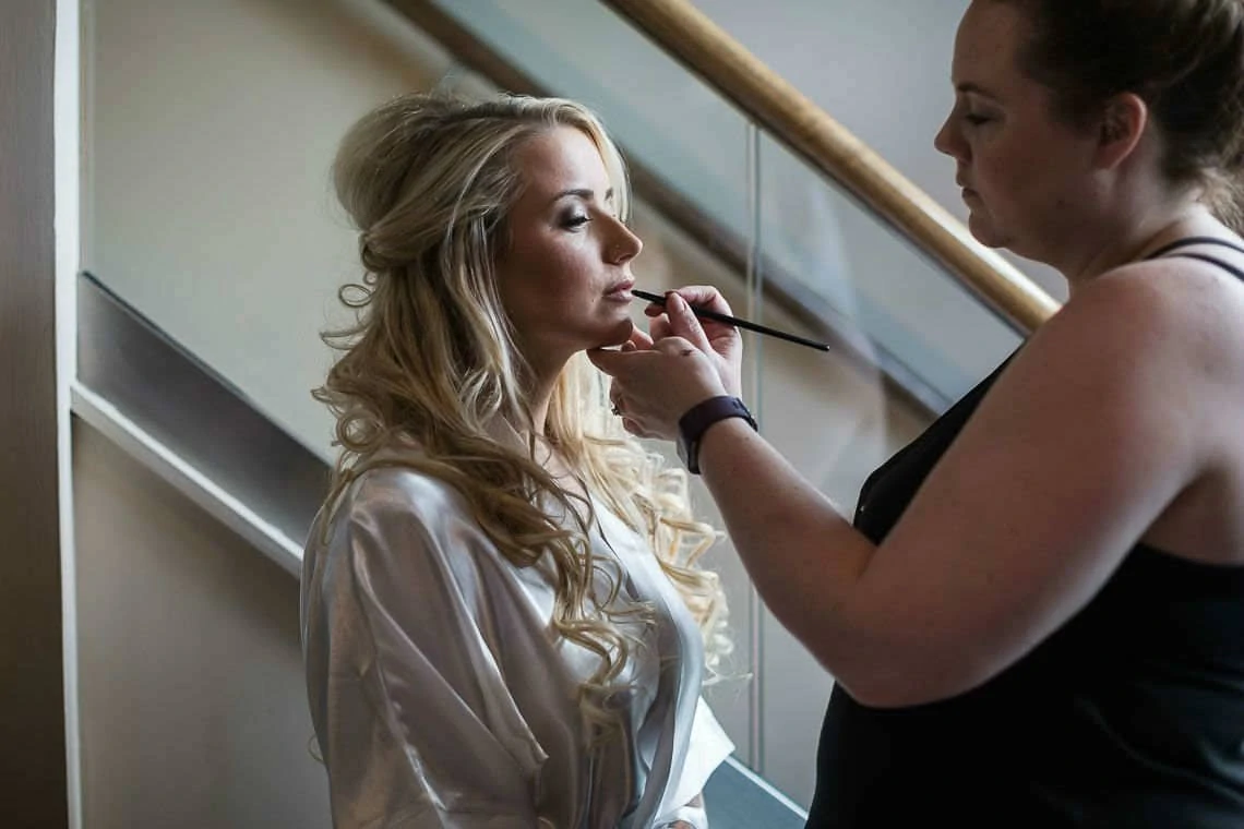 bride getting lipstick applied by make up artist