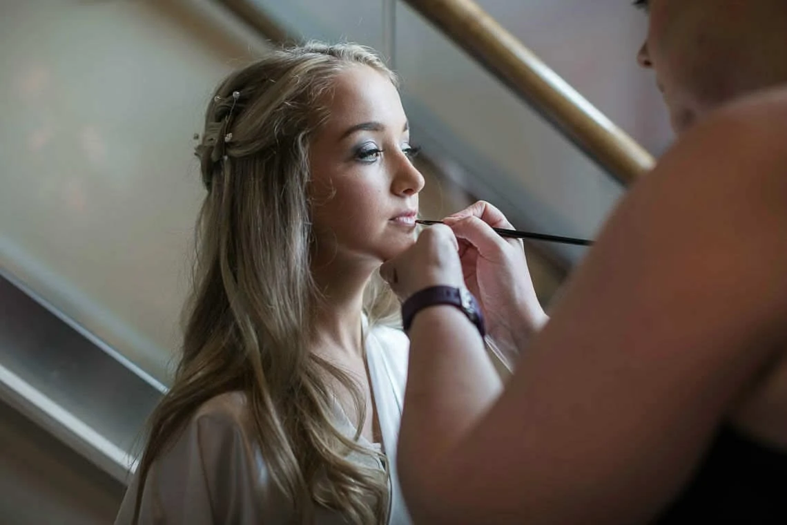 bridesmaid getting lipstick applied by make up artist