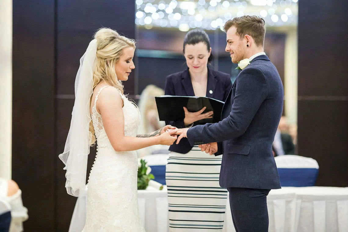 Bride places wedding ring on groom's finger during humanist wedding ceremony