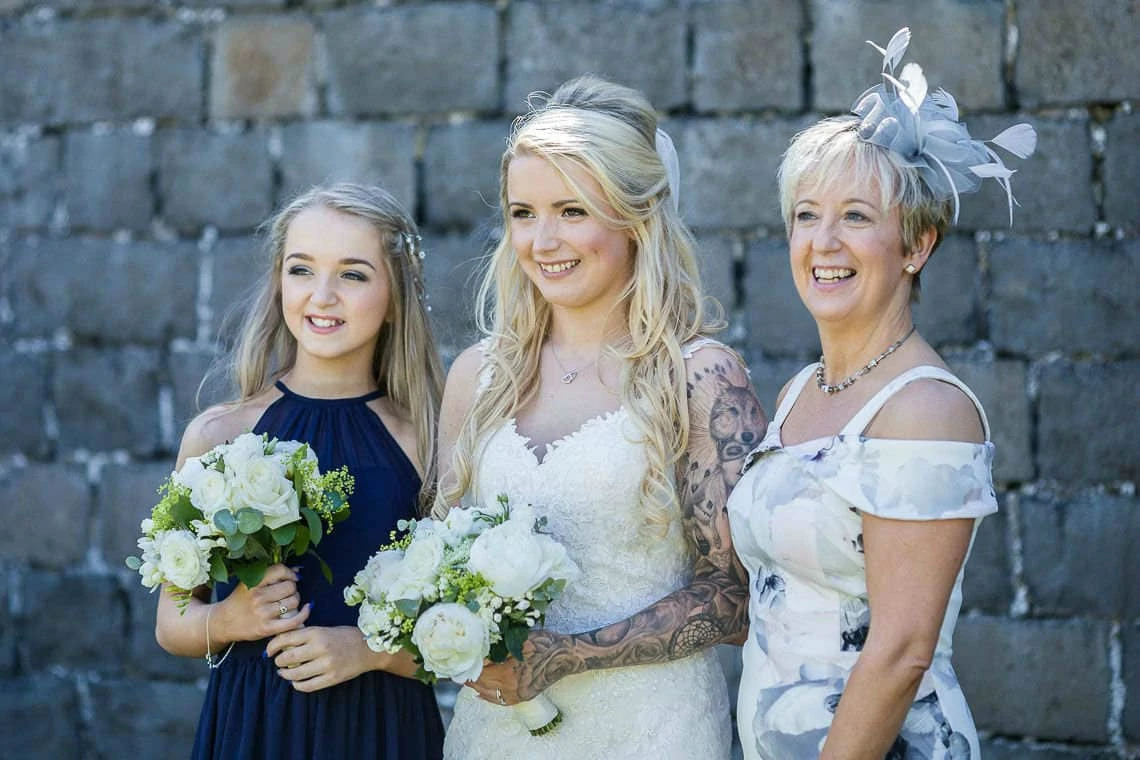 Bride, bridesmaid and mother of the bride smile for photo