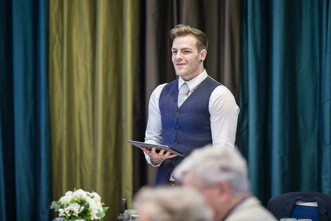 groom smiling whilst doing his wedding speech at evening reception