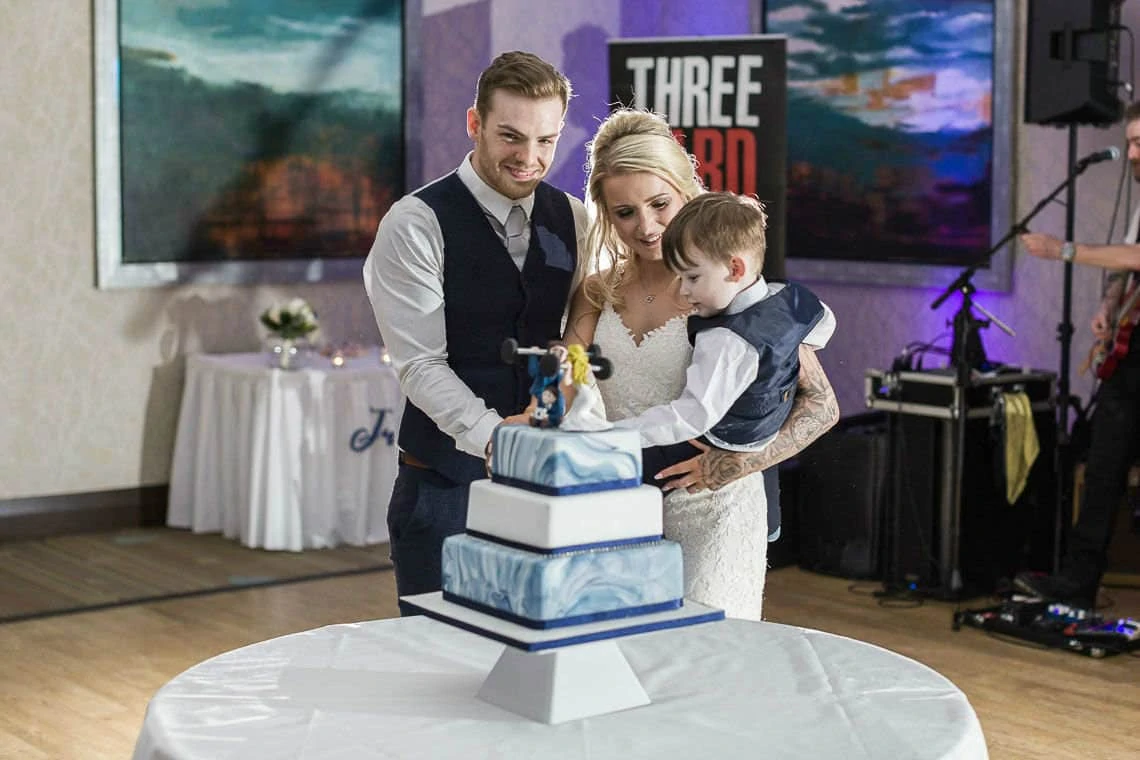 Garden Suite - newlyweds cut wedding cake with small child at evening reception