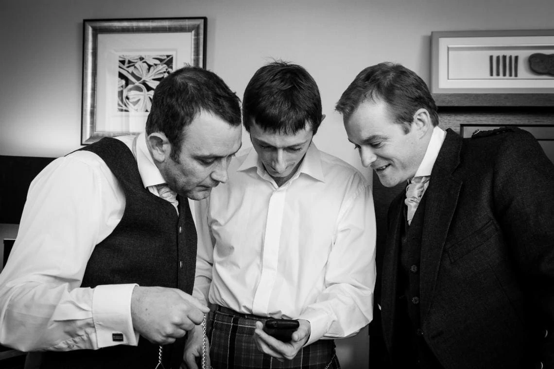 groom and friends checking out how to tie a cravat
