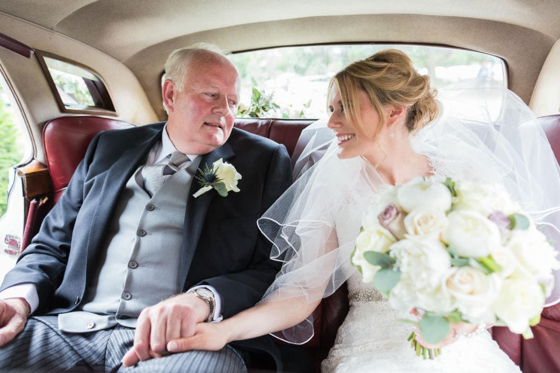 bride and her father looking at each other in the back of a classic Rolls Royce
