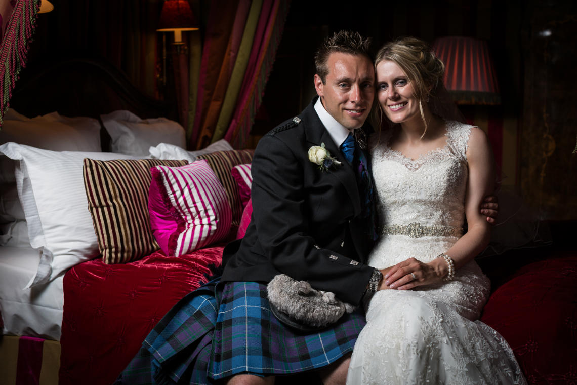 newlyweds embrace sitting on a bed in their suite