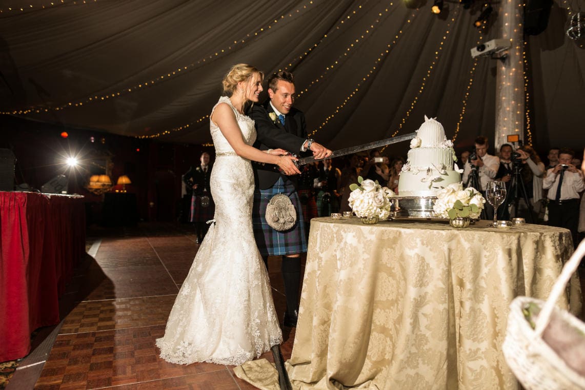 newlyweds cut the cake with a sword in the Stables Ballroom