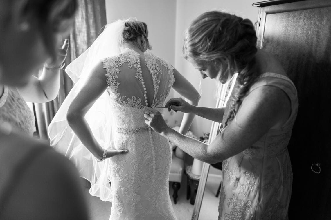 bride's wedding dress being buttoned up