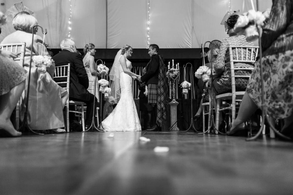 ceremony viewed low from the rear of the aisle in the Stables Ballroom