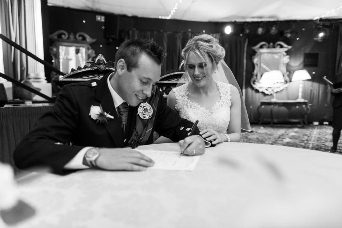 newlyweds signing the marriage schedule in the Stables Ballroom