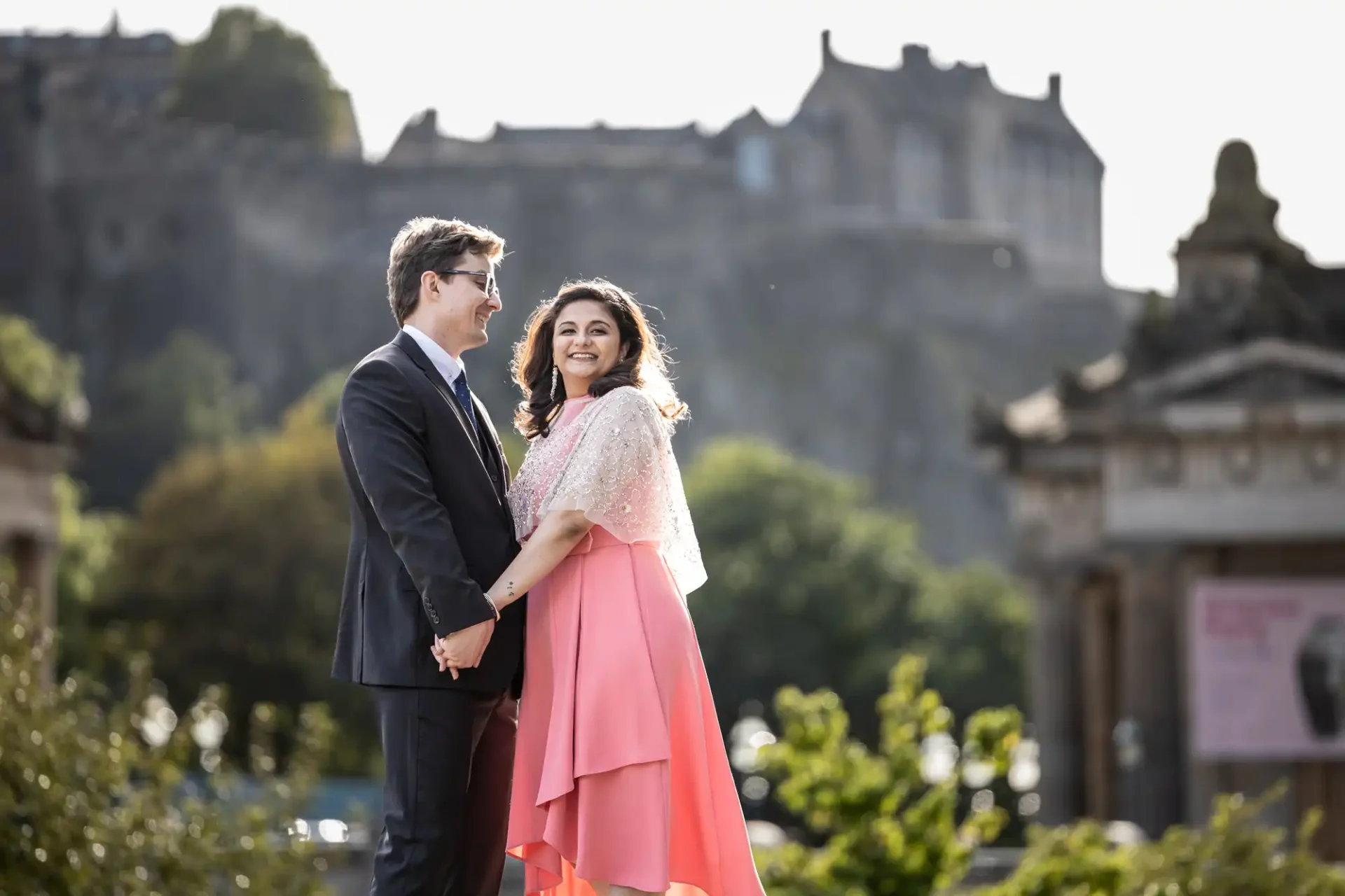 The Scotsman Hotel wedding photos: A man and woman holding hands, smiling at each other, standing outdoors with a historic building in the background.