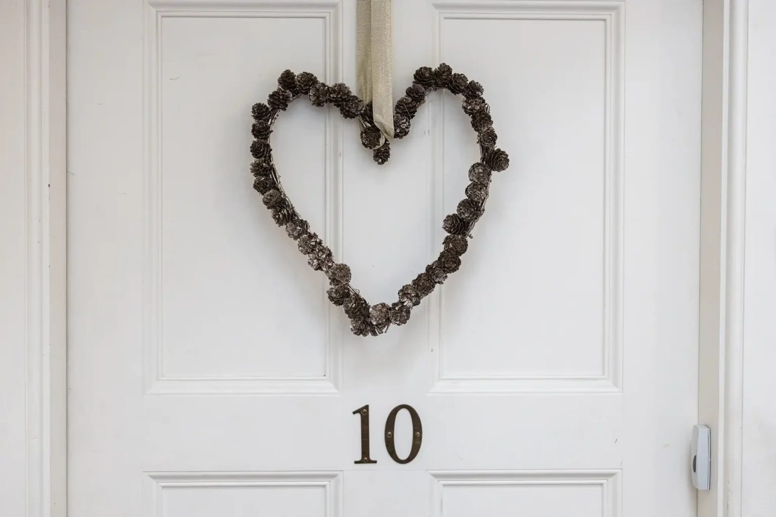 Riddles Court wedding photos: A heart-shaped wreath made of pine cones hangs on a white door with the number 10.