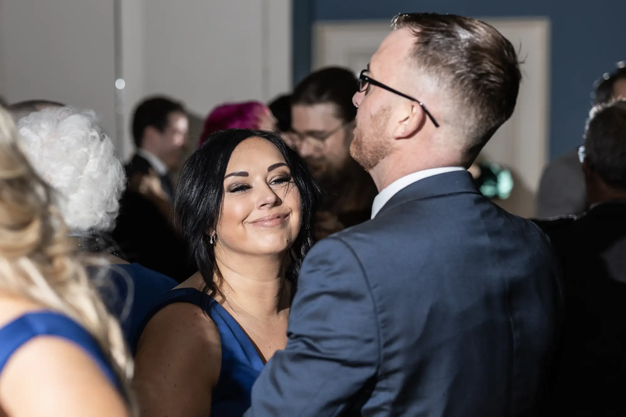 A woman in a blue dress and a man in a suit smiling at each other at a formal event.