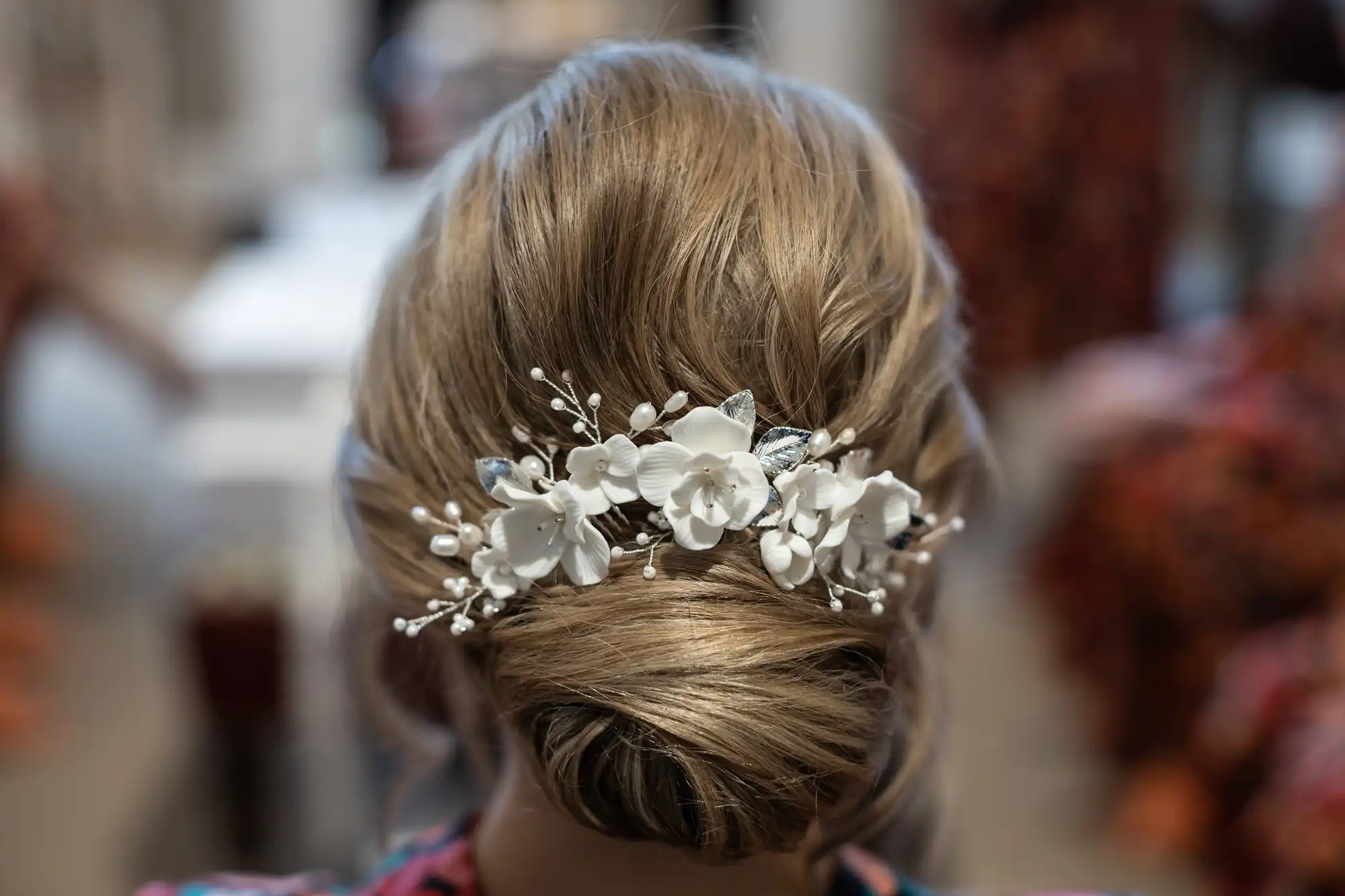 Rear view of a woman's hairstyle featuring an elegant updo accented with white floral and silver hair accessories.