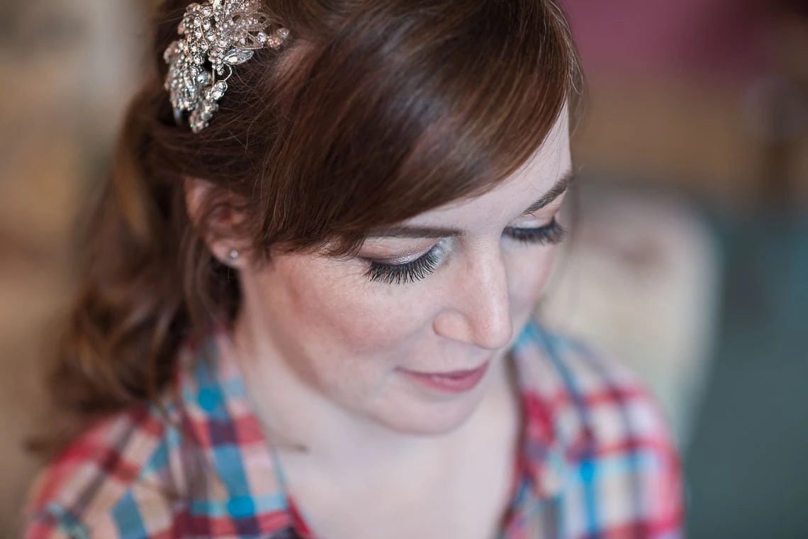 A woman with a decorative hair clip, wearing makeup, looking downwards in a thoughtful pose.
