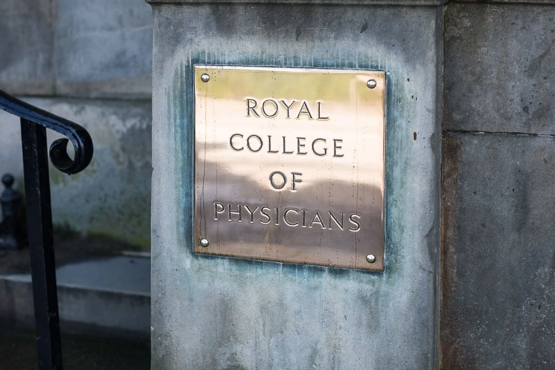 Brass plaque on a stone pillar reading "royal college of physicians" with a subtle reflection and a black handrail visible on the left.
