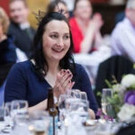 photo of guest smiling and clapping during speeches at wedding reception