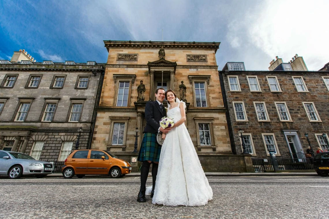 newlyweds standing outside the Royal College Of Physicians Of Edinburgh on Queen Street