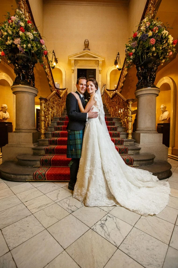 newlyweds standing at the bottom of the grand staircase in RCPE