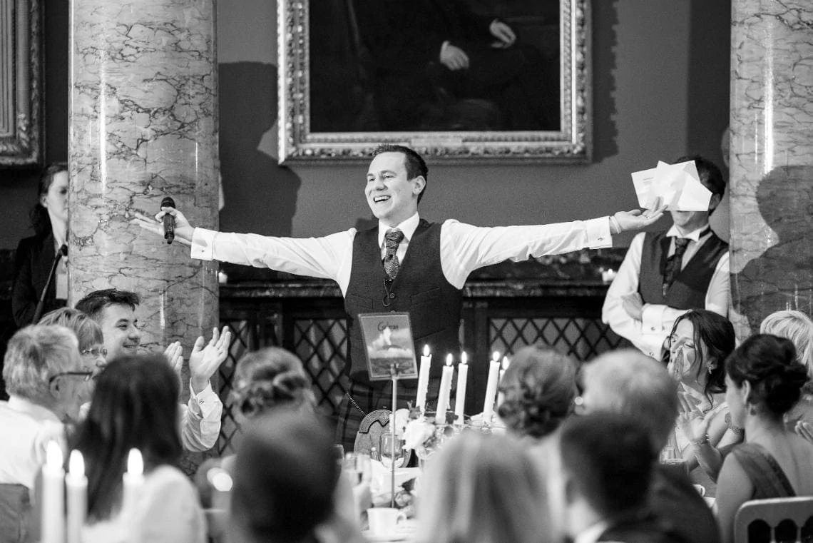 groom with raised arms during his speech in the Great Hall