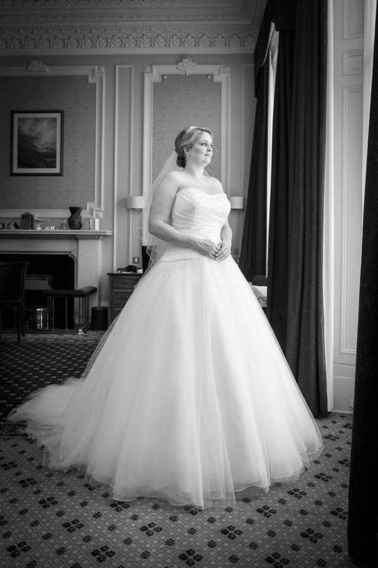 bride in dress profile photo looking out the window of her suite at the Royal Terrace Hotel