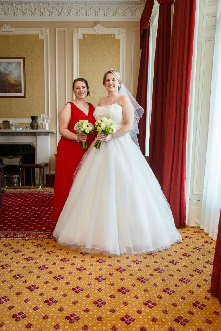 bride in white dress and bridesmaid in red dress in bedroom suite at the Royal Terrace Hotel