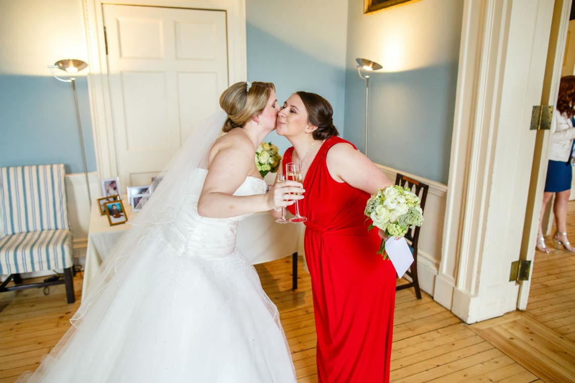 bridesmaid wearing a red dress congratulates newlywed bride in the Cullen Suite
