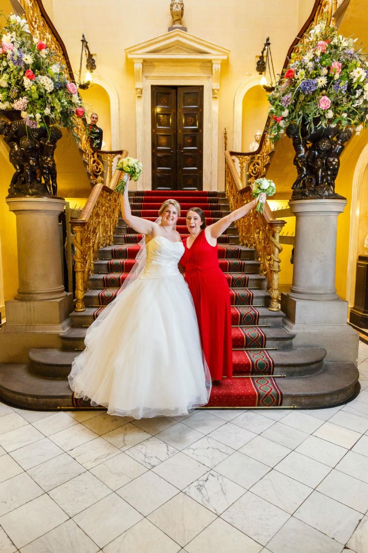 bride and bridesmaid wearing a red dress standing on the grand staircase