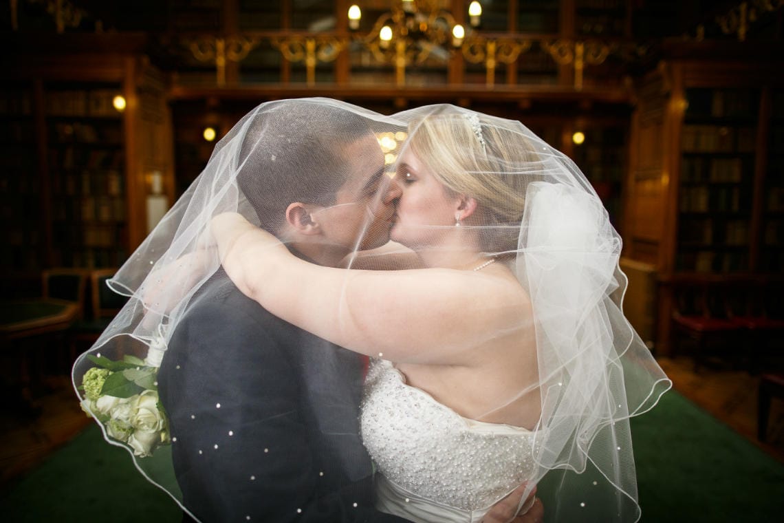 newlyweds kissing under the bride's veil in the New Library