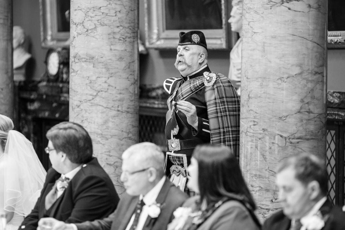 Pipe Major Iain Grant announces the speeches in the Great Hall