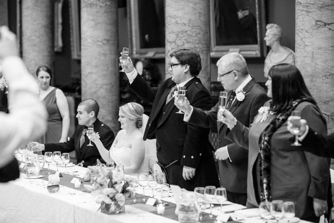 guests raise a toast at the end of the father of the bride speech in the Great Hall