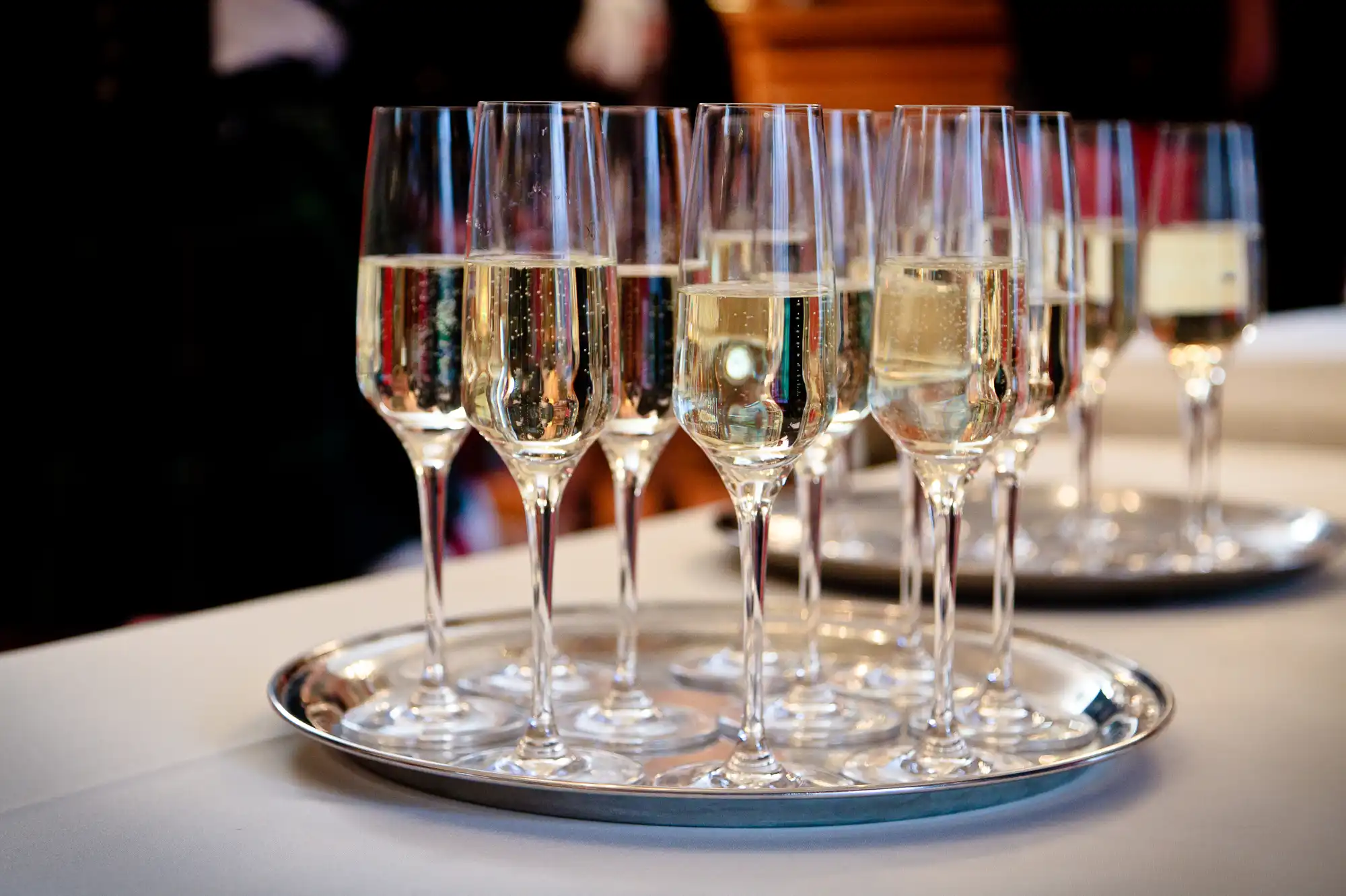 A tray of champagne glasses filled with sparkling wine, placed on a table at a formal event.