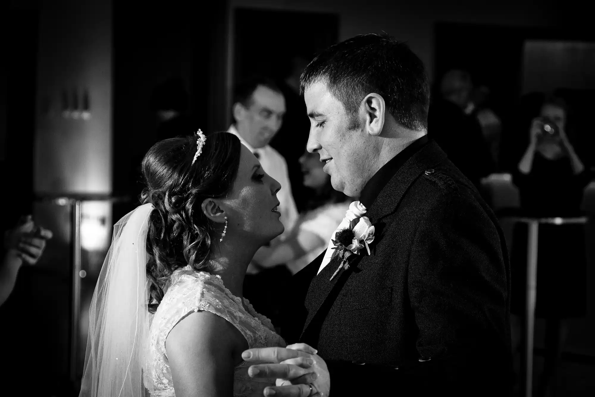 Bride and groom sharing an intimate moment during their wedding dance, captured in black and white.
