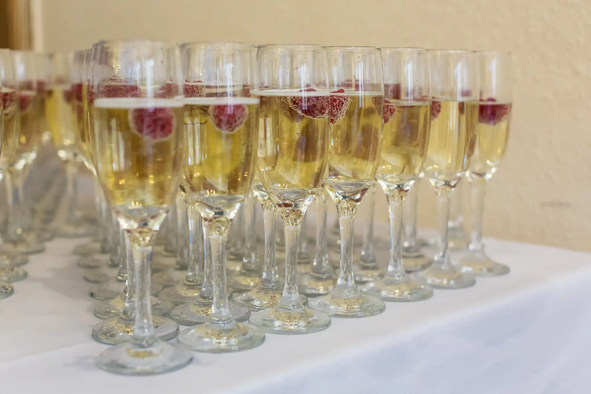 Glasses of champagne with raspberries on a table, lined up for a celebration.